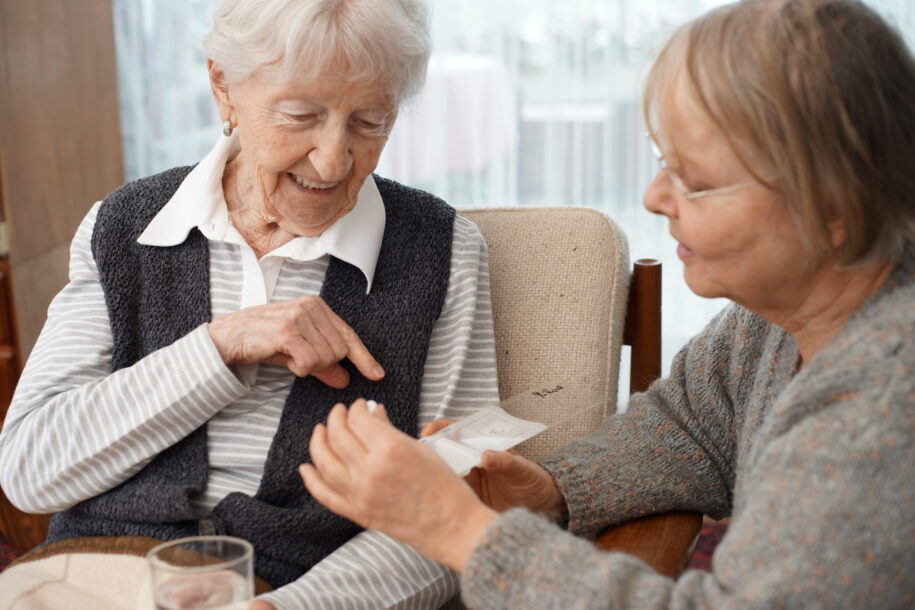 Woman at home with caregiver choosing a medication demonstrating a daily task when to call hospice